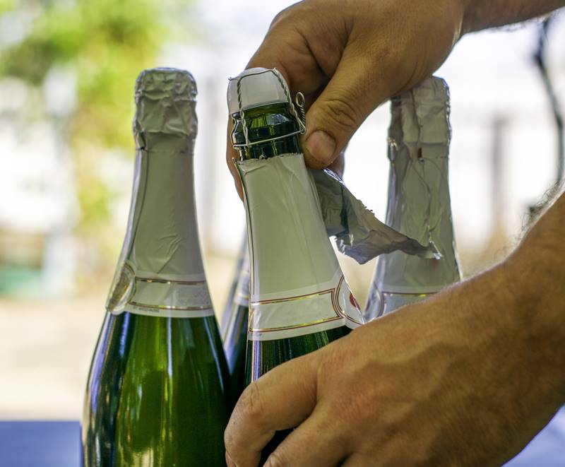 a man opens a bottle of champagne standing on a table in the garden